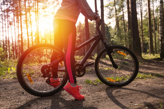 Woman riding a mountain bicycle along path at the forest