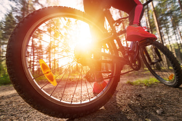 Woman riding a mountain bicycle along path at the forest. Closeup on pedal and foot