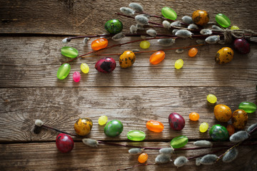 Easter eggs and willow branches on wooden background