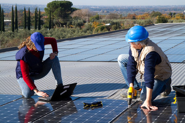 young engineer girl and an elderly skilled worker fitting a photovoltaic plant