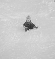 Fototapeta na wymiar black and white, a child riding on the hill in the winter.