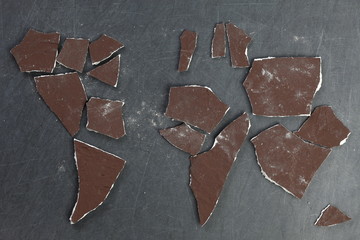 The cracked and broken pieces of concrete wall arrangement in to the world map shape represent the world and construction material concept related idea.