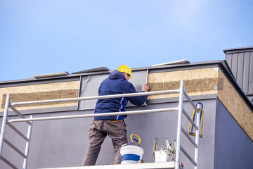 Fototapeta premium Roofer assembles sheet metal on the roof. Roofers on the roof.