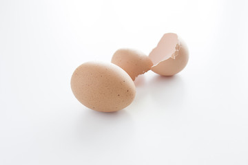 Uovo di gallina intero e guscio d'uovo aperto su sfondo chiaro