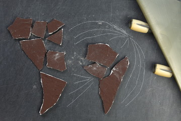 The cracked and broken pieces of concrete wall arrangement in to the world map shape put beside the wing part of plastic model toy plane represent the world and logistic business concept related idea.