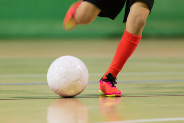 Football futsal training for children. Indoor soccer young player with a soccer ball in a sports...