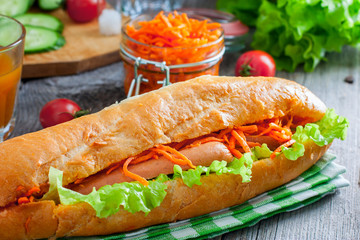 Hot dog with sausage, carrots and sauce, selective focus