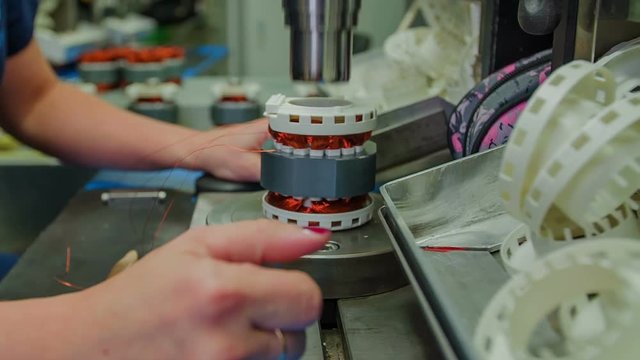 A robotic machine presses down on an item. The item becomes a bit smaller. Then a woman takes it to cut some parts off.

