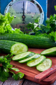 Fresh green chopped cucumber and fresh herbs on a wooden board, selective focus