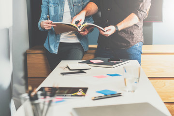 Young business woman and businessman standing at table and look in directory.Man is pointing to page in book.