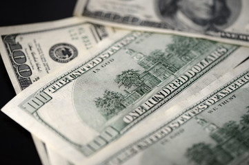 A pack of hundred dollar bills on a dark background