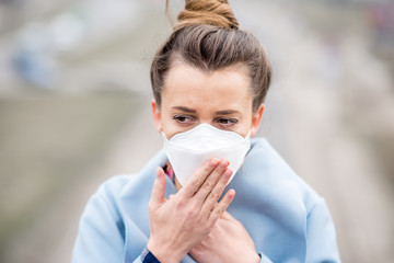 Young woman in protective mask feeling bad in the city with air pollution from traffic and...