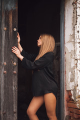Sensual blonde girl in black shirt waiting near a door
