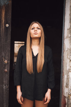 Sensual blonde girl in black shirt waiting near a door
