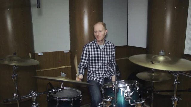 Handsome guy behind the drum kit in shirt and trousers plays the drums