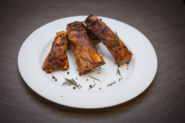 Pork ribs, BBQ grilled, with seasonings on a white ceramic plate