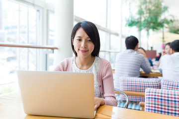 Woman working on laptop computer in coffee shop