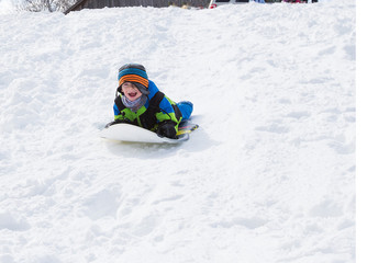 Fototapeta na wymiar Boy riding a sled tobogganing in the snow