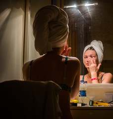 Woman at mirror doing makeup