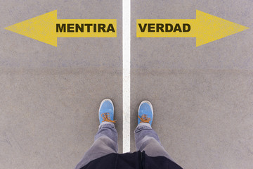 Mentira y Verdad, Spanish text for Lies and Truth on asphalt ground, feet and shoes on floor