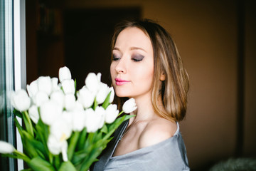 Naklejka premium A girl holds a bouquet of white tulips