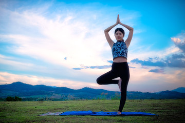 Fototapeta na wymiar Woman practicing yoga pose outdoors over sunset sky background.