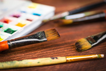 Fototapeta premium artist workplace with colorful dye and instruments, brushes on wooden table close-up