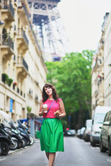 Naklejka na ściany i meble French woman walking with coffee to go and baguette on a street of Paris