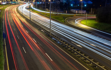 Fototapeta na wymiar Light trails on a highway turn during evening rush hour
