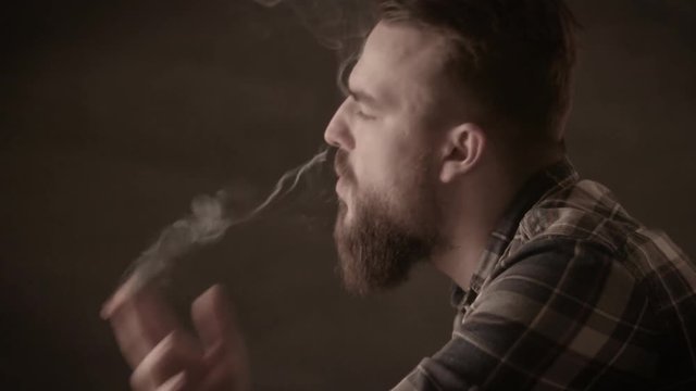 Handsome man with a beard smoking cigar in studio.A man with a beard cigar burns