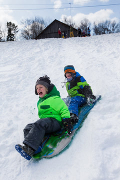 Boys riding a sled, tobogganing down the snow