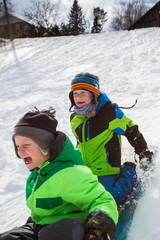 Fototapeta na wymiar Boys riding a sled, tobogganing down the snow