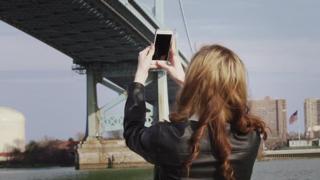Young woman taking pictures of landmarks with smartphone