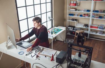 A man graphic designer working in his 3d printing studio.