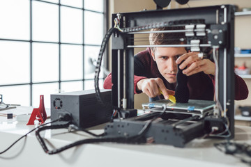 A men detaching new made object from 3d printer.