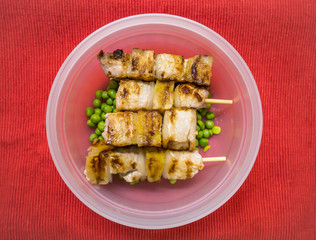 Pork meat skewers with green peas in a box for lunch