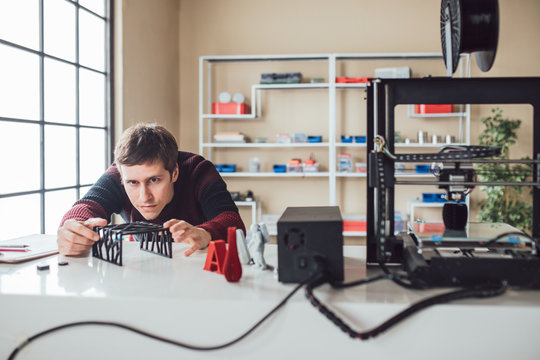 Graphic designer measuring objects made on 3d printer at his studio.