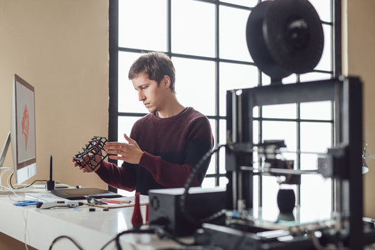 Graphic designer measuring object made on 3d printer.