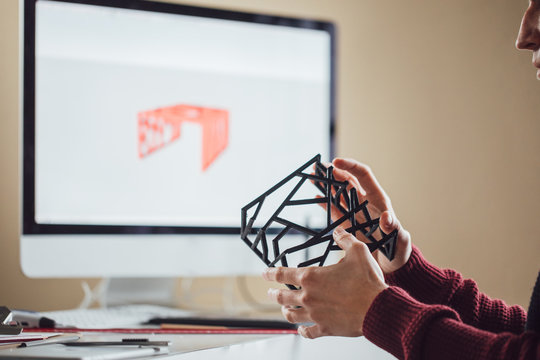 A man graphic designer doing quality control of object made on 3d printer.
