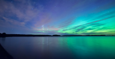 Fototapeta na wymiar Northern lights dancing over calm lake 
