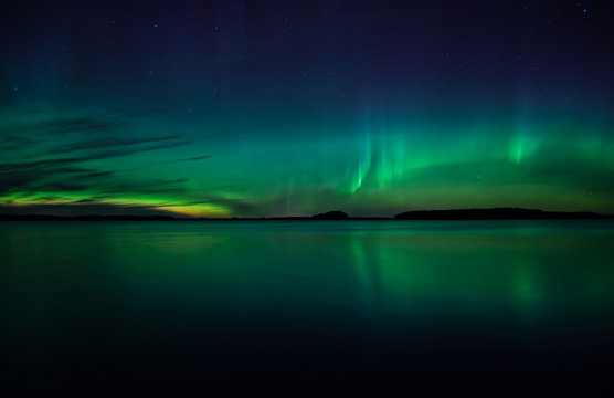 Northern lights dancing over calm lake 