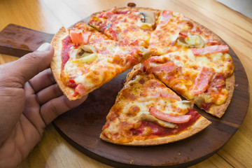 hand holding slice pizza.
