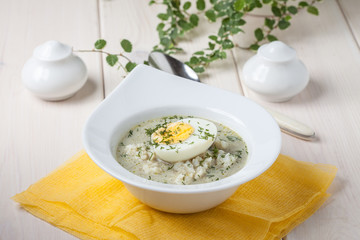 Sorrel soup with egg in white bowl.
