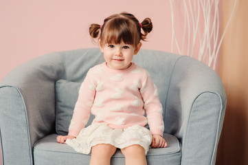 close up indoor portrait of cute happy 2 years old baby girl in pink sweater