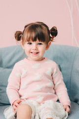 Fototapeta premium vertical close up indoor portrait of cute happy baby girl in pink sweater