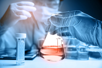 Flask in scientist hand with laboratory background 