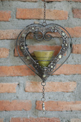 The heart-shaped candle lamp was hung on a brick wall.