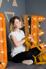 Young woman sitting and holding merino wool near LOVE sign