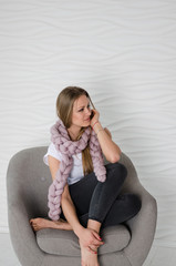 Beautiful woman in soft pink merino wool scarf sitting on arm chair