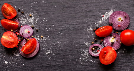 Banner top view on ingredients for a healthy salad with cherry tomatoes and onion on natural black...